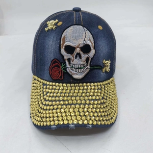 Detail of blue washed denim baseball cap with skull embroidery and golden rhinestones