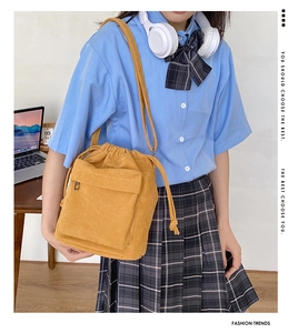 Ginger yellow corduroy drawstring bucket bag with front pocket shown in lifestyle setting