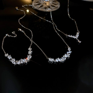 Detailed close-up of V-shaped silver necklaces and bracelet set with sparkling zircon stones