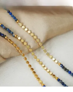 Detailed macro view of gold-plated beads and blue lapis lazuli stones on a steel necklace