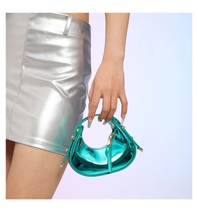 Detail of green metallic leather handbag with studs and tassel on silver skirt