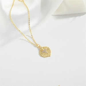 Elegant gold sunburst heart necklace with sparkling zircon pendant on white silk