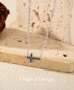 Detail of S925 silver necklace with blue cross pendant hanging on a natural stone