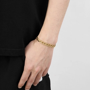 Détail d'un bracelet gourmette NK en acier titane doré minimaliste sur un poignet masculin