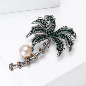 Detailed close-up of palm tree brooch with green rhinestones and faux pearl accent