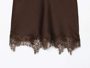 Détail de l'ourlet de robe en soie marron foncé avec bordure en dentelle et tissu satiné