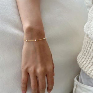 Close-up of minimalist gold chain bracelet featuring elegant natural freshwater pearls