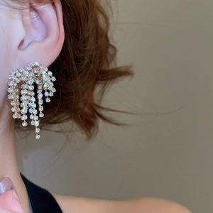 Close-up of elegant gold tassel earrings with shimmering rhinestones worn by a model