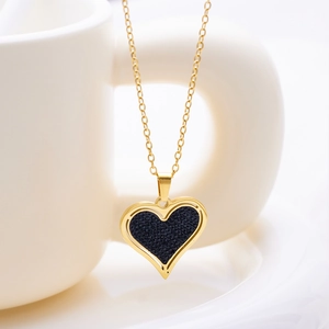 Primer plano del collar corazón dorado con incrustación negra colgado de un asa de cerámica