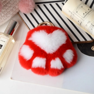 Detail of soft red plush cat paw keychain with white heart pad and golden ring