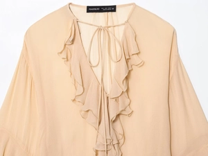 Close-up of v-neck apricot chiffon blouse with delicate ruffles and tie-up details