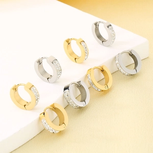 Detail of sparkling crystal-encrusted huggie earrings in gold and silver stainless steel