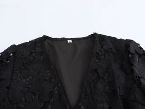 Dettaglio dello scollo a V del top in pizzo con motivi floreali ed etichetta taglia S