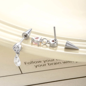 Silver drop earrings with pink heart gemstone and clear zircon on a book background