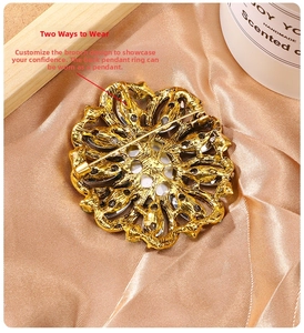 Close-up of golden hollow flower brooch with dual-use pin and pendant loop on silk