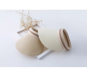 Dettaglio di visiere in paglia beige e bianco crema con nastro decorativo a righe
