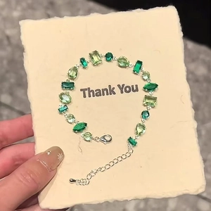 Detail showing sparkling green zircon bracelet with various cuts on a thank you gift card