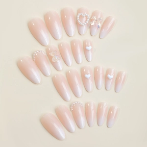 Pink ombre press-on nails with 3D bears, pearls, and heart charms in a long oval shape
