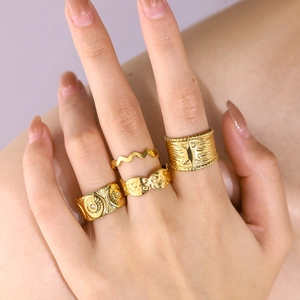 Set of four gold stainless steel rings with star and sun patterns on model's hand