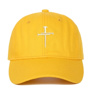 Close-up of cross embroidery on yellow cotton baseball cap with detailed stitching