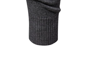 Vue macro d'un pull en maille gris foncé montrant le tissu et les poignets côtelés