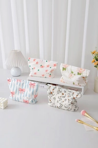 Dettaglio di quattro trousse in tela floreale con motivi eleganti ed etichette H&R BAG
