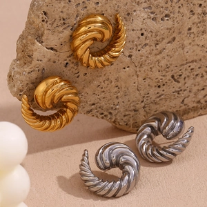 Macro shot of spiral horn stud earrings in gold and silver finish on natural stone