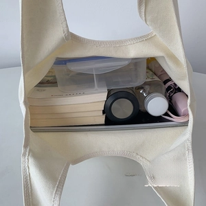 Vista interna della grande borsa tote in tela bianca con libri, lunch box e ombrello
