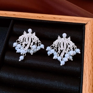 Macro shot of silver metal ear cuffs with cubic zirconia and pearl tassel fringe