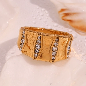 Detailed close-up of wide 18K gold plated ring with micro-pave diamonds on stone texture