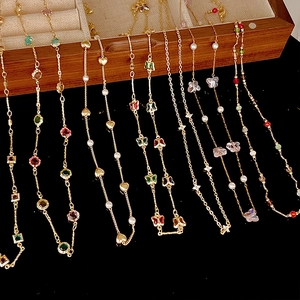 Detail of colorful zircon necklaces with butterfly charms and pearls on wooden box