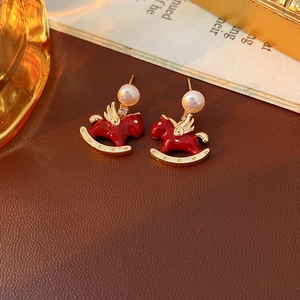 Detailed view of red enamel rocking horse earrings with pearls and gold wings