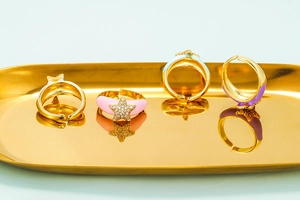 Detail of adjustable star rings with enamel and rhinestones on a gold jewelry tray