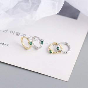 Detailed shot of beaded gold and silver S925 sterling silver hoop earrings with green zircon