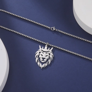 Detailed macro view of a silver crown lion pendant with box chain on minimalist display
