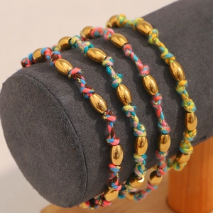 Détail d'un bracelet tressé à la main avec perles en acier doré 18K et cordon coloré