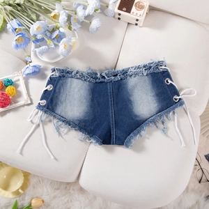 Dettaglio di pantaloncini in denim blu con lacci laterali e bordi grezzi sfilacciati