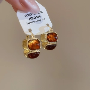 Close-up of square amber resin earrings with textured 925 silver gold-plated base