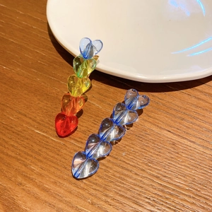 Colorful heart-shaped acrylic hair clips set on wooden table with a white ceramic plate