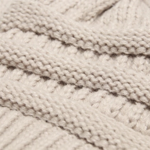 Macro shot of beige thick-knit beanie texture showing premium yarn and warm weave detail