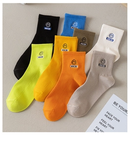 Detail view of colorful cotton crew socks featuring embroidered smiley faces and Nice text