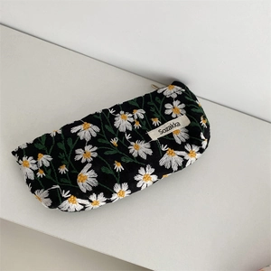 Detail of floral daisy embroidery on black canvas cosmetic bag with zipper