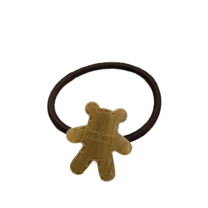 Cute brown bear hair tie made of resin with golden Amy bear engraving on white background