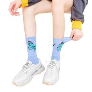 Light blue crew socks with butterfly pattern made of combed cotton worn by a model