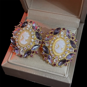 Detailed view of vintage cameo earrings with purple gems and crystals in a box
