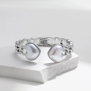 Detail showing the silver chain link bracelet with pearl heart charms on stone base