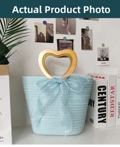 Detail of light blue woven handbag featuring a gold heart handle and organza bow decoration