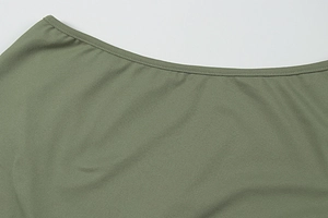 Makro-Detail von olivgrünem Strickstoff mit präzisen Nähten am Sommerkleid