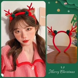 Detail view of red Christmas reindeer antler headband with festive green fur balls and glitter