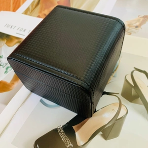 Elegant black textured watch storage box with embossed pattern and stylish accessories
